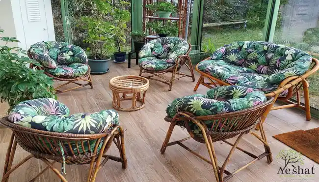 تشک صندلی باغی طرح استوایی روی صندلی حصیری در تراسی با کفپوش چوبی و گلدان در اطرافش-1