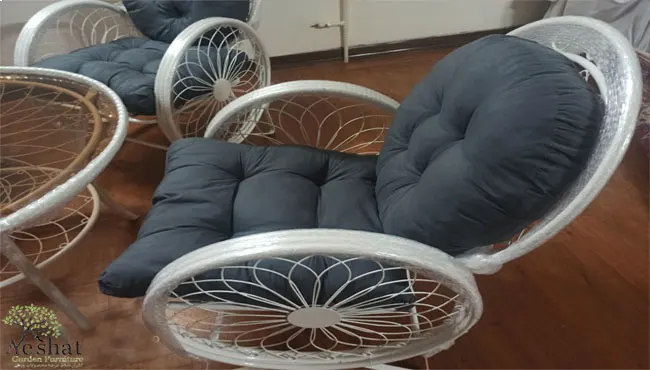 تشکچه صندلی باغی طوسی پر رنگ روی صندلی گلبرگ سفید در فضای درون خانه با کفپوش چوبی