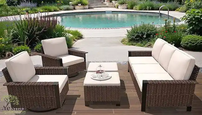 ست مبلمان باغی حصیری قهوه‌ای شامل مبل سه‌نفره، دو صندلی تک و عسلی با تشک‌های کرم روشن، قرار گرفته کنار استخر - گالری نشاط