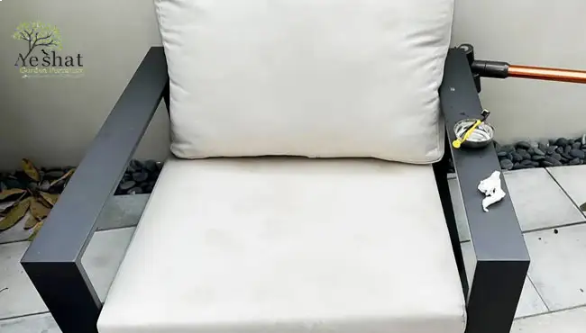 فردی در حال تمیز کردن تشک صندلی باغی سفید با جاروبرقی